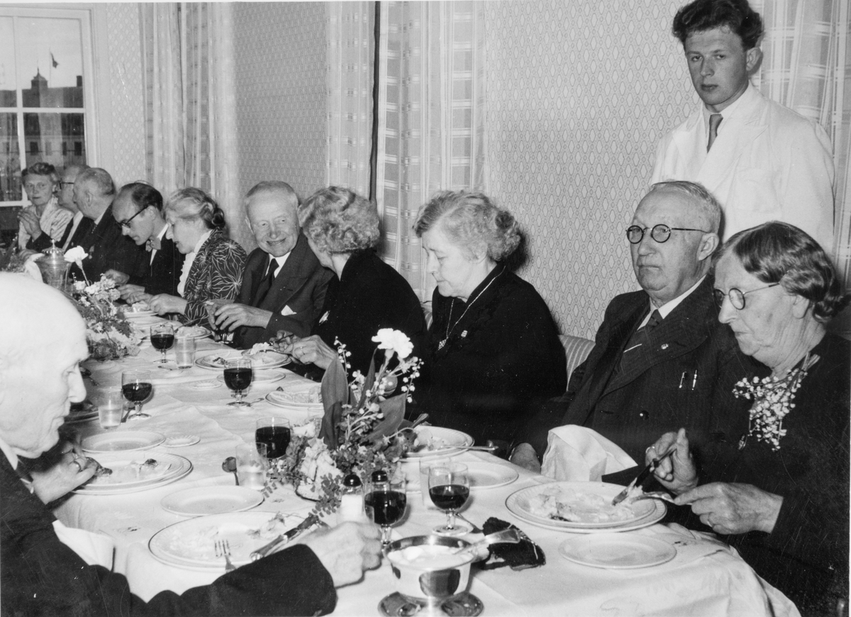 Festmiddag på Grand. Bak gjestene står en servitør.