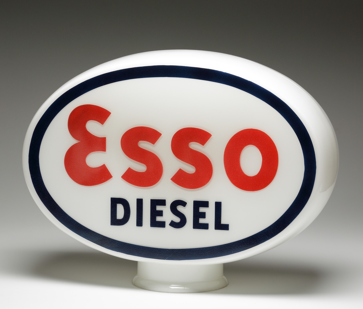 Reklamlampa/skyltglas för Esso.
Oval kupa av opakt mjölkglas. På de platta sidorna försedd med en målad, svart ring, därinom ett rött "Esso" och i svart "Diesel".
Glaset satt överst på bensinpumpen.
Bolaget "STANDARD" bytte namn till "ESSO" den 15 maj 1939 ("Mackboken" sid 17, av Kjell Eliasson och Ewa Forsberg). Smålands museum fick glaset av Böhlmarks 20 nov 1938: Troligen är det bland de första Esso-skyltarna som tillverkades i Sverige.
Blåst fast i form. Målad text enligt ovan.

Inskrivet i huvudkatalogen 1939.