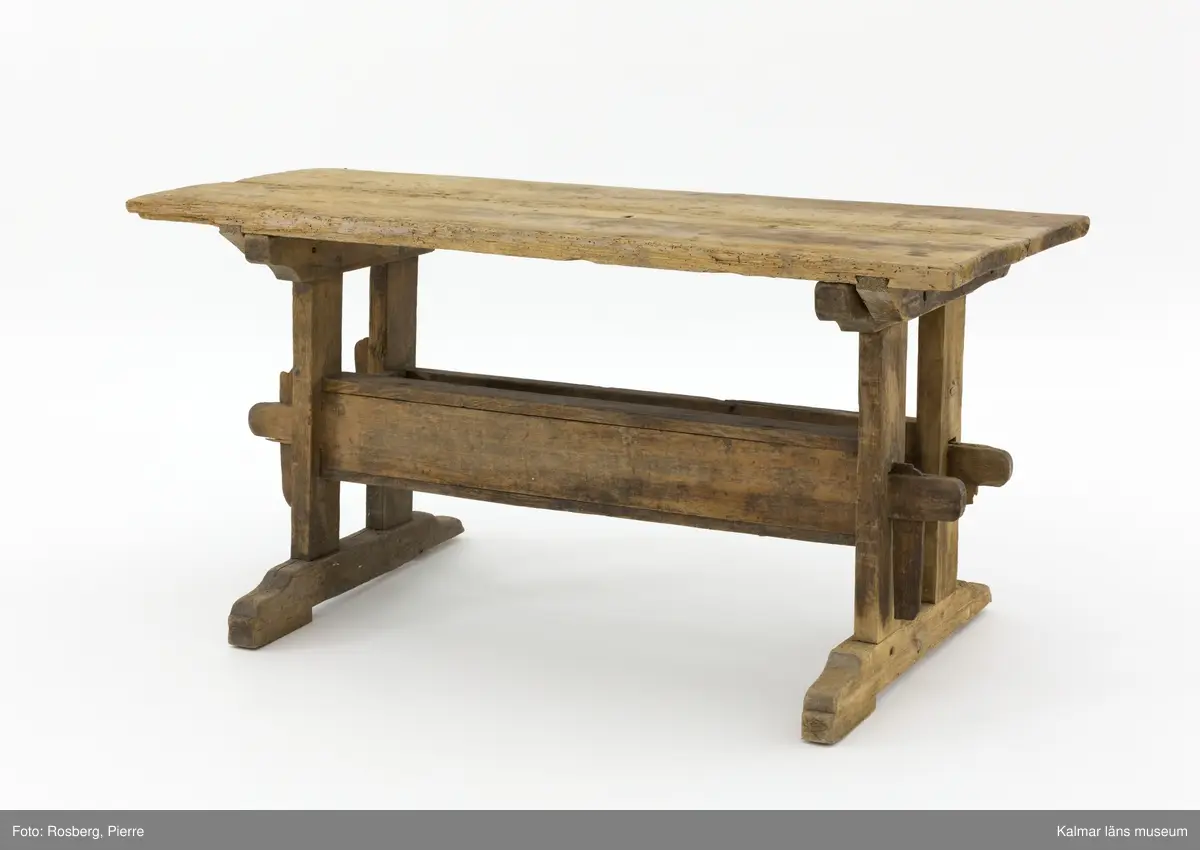 KLM 11169. Bord, långbord. Av furu. Avlångt bord med två ben på vardera kortsida samt lös bordsskiva med rektangulär form. Undertill en avlång låda som håller samman benen. Omålat. Väl använt.