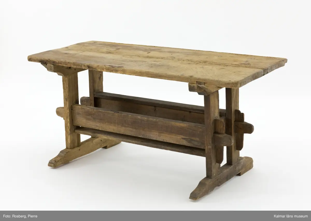 KLM 11169. Bord, långbord. Av furu. Avlångt bord med två ben på vardera kortsida samt lös bordsskiva med rektangulär form. Undertill en avlång låda som håller samman benen. Omålat. Väl använt.