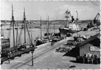 Fraktfartyg vid stora hamnkajen. Gods upplagt på hamnplanen. Vykort med tandad kant.