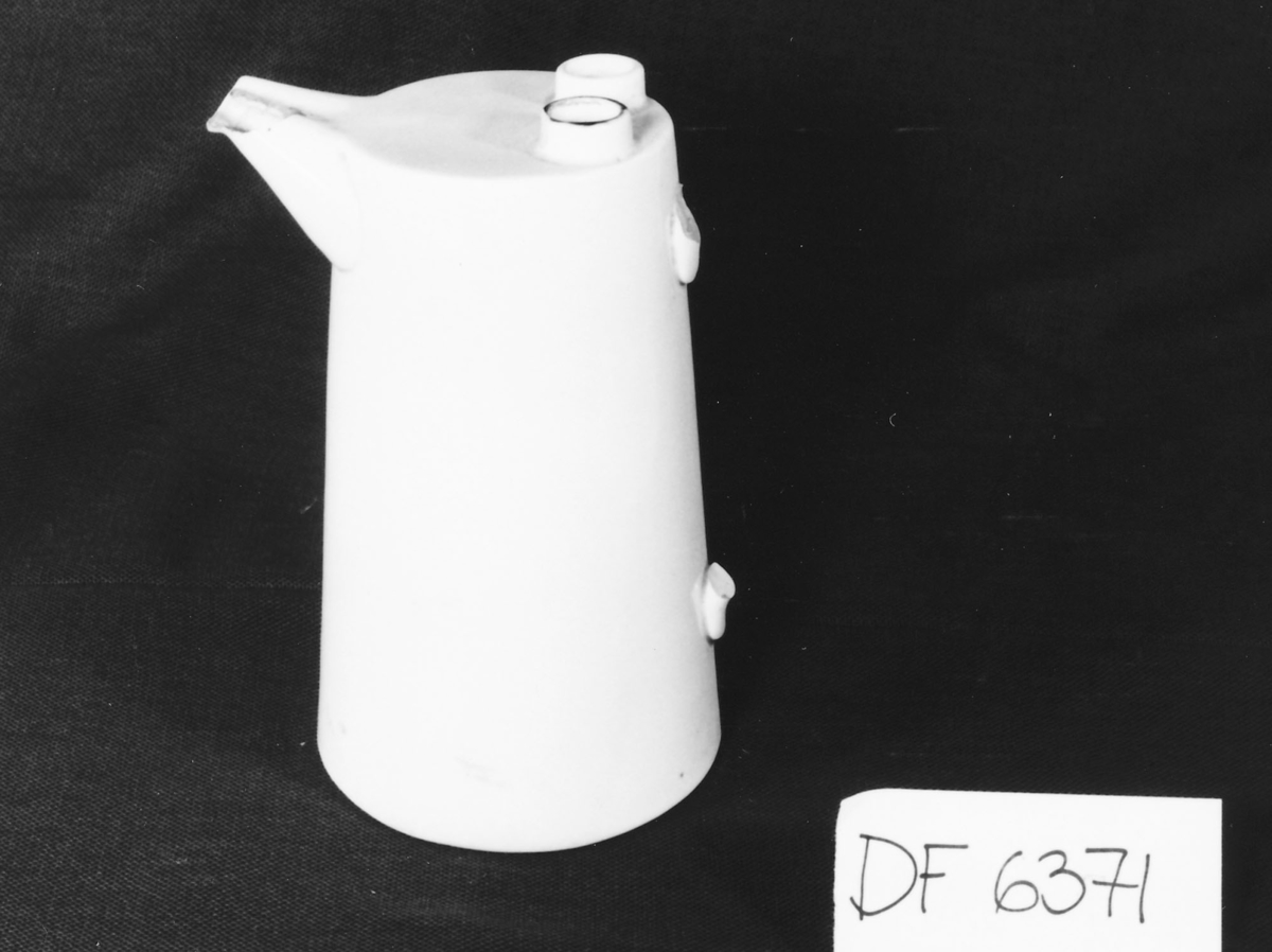 Kannen har dobbel tut og to hull oppå.