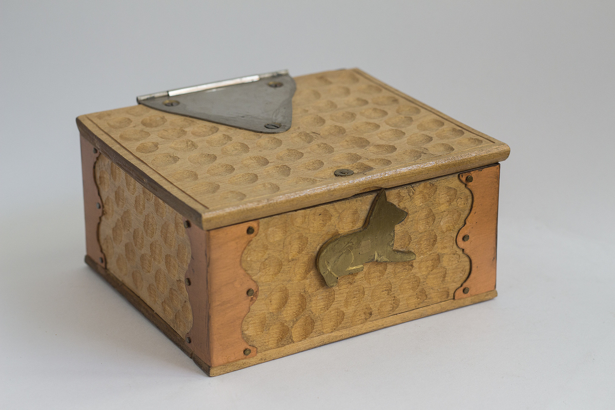 Rektangulært skrin med metallbeslag. Låsen er en metallhund