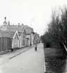 Stadsvy med bostadshus och pojke med cykel på gatan.