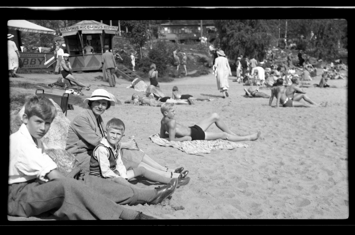 Hilda Sundt sitter sammen med sine sønner Rolf jr. og Lars Peter på stranden på Hvalstrand bad. Fotografet 1936.