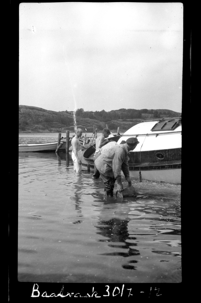 Rolf Sundt sr. står bakerst sammen med to menn og vasker en motorbåt, Hvasser. Fotografert 1917.