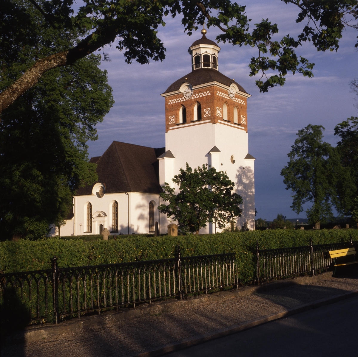 Nationaldagen i Bollnäs 6 juni 1999. Solen lyser på Bollnäs kyrka omgiven av grönska.