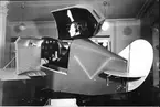 F6 Karlsborg 1943. Flottiljens Link-Trainer (nuvarande flygsimulator). Påverkades vid roderrörelser som ett riktigt flygplan. Albumet är en del av en donation från Karl-Axel Hansson, Karlsborg. Förteckning över hela donationen finns i albumet samt som Word-dokument.