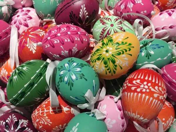 Fargerike, håndmalte påskeegg med mønstre, utstilt på Norsk Folkemuseums påskeutstilling. Eggene har detaljerte blomstermotiver i ulike farger som grønt, rødt og gult, og er pyntet med hvite bånd.