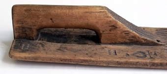 Svagt böjt mangelbräde, avsmalande framåt. Handtaget är skuret i ett stycke med brädet. Invid handtaget är två inskurna hjärtan, krönta med ett kors samt initialer. Brädet är rikt dekorat med nagel- skåljärn- och kilsnitt, samt fem utskurna hjärtan. Brädet är svagt ryggat och brädets främre del är kraftigt upphöjd.
