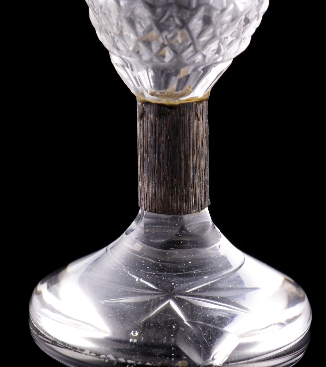 Brännvinsglas med metallben. 
Slipat, med graverad bladdekor.