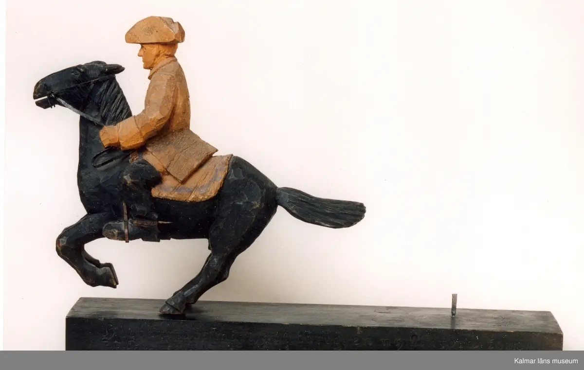 KLM 39255:31. Skulptur, av trä, bemålad. Ryttare till häst, Karl XII. Figur stiftad mot träplattan. Ryttaren har uniformsrock och hatt av karolinermodell samt bär sporrar. Hästen är utrustad med träns och betsel i svartmålad plåt, smidda stigbyglar i koppar samt randmålad sadel i blått och bronsfärg(?). Signerad, H.C. På hästens ländrygg samt på plattans ovansida. Inristad kursiverad text på plattans långsidesfront, E. Tegners tex: Högbarmad, smärt, gullhårig, en ny Aurora kom, Från Kämpe tjugoårig hon vände ohörd om. Datering, omkring 1930. Tillverkad av Helge Rugland, f. Carlsson.
Figuren hör samman med KLM 39255:17 Aurora Königsmarck, vilka utgör en figurgrupp, benämnd, Karl XII och Aurora Königsmarck.