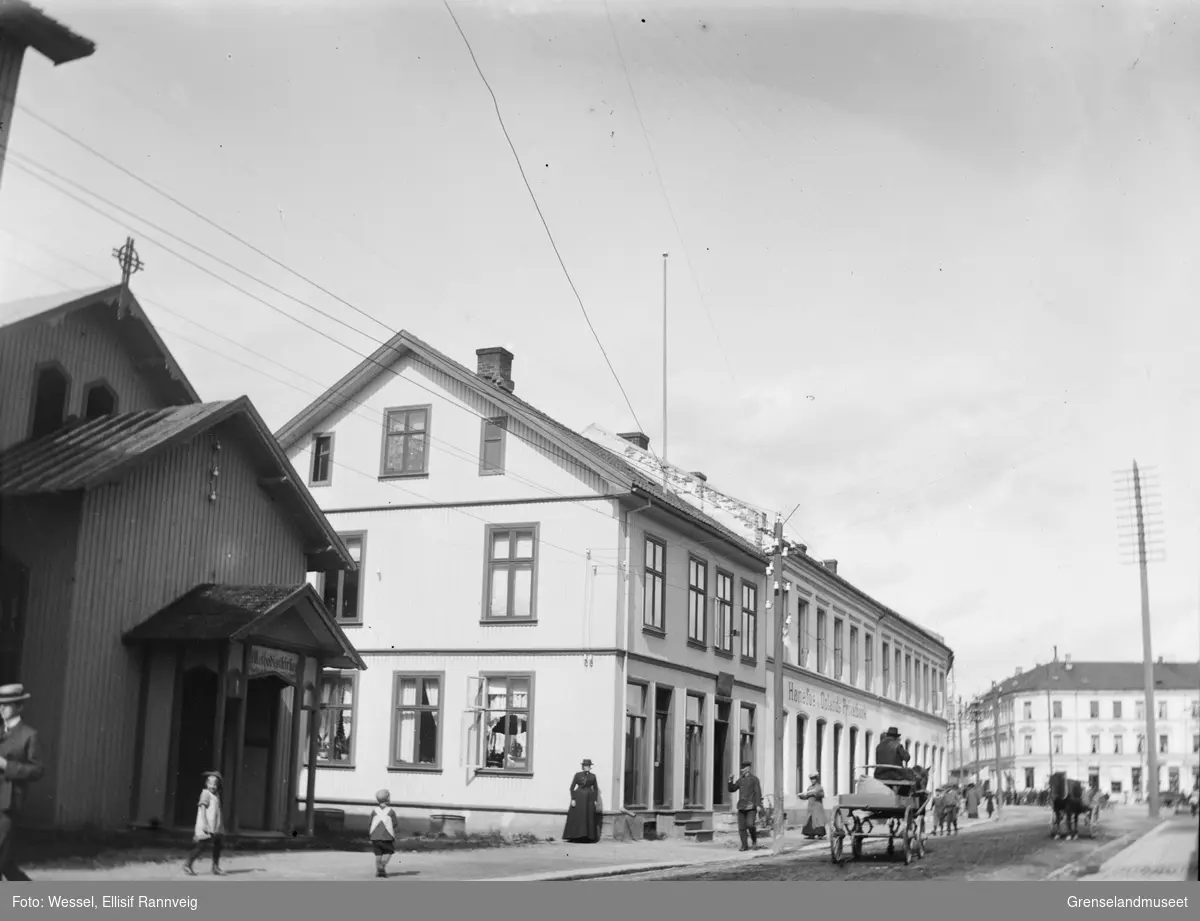 Gatebilde fra Hønefoss, 1901. Vi ser Methodistkirken til venstre og Hønefos og Oplands Privatbamk midt i bilde. Mange mennesker og hest og kjerrer i gaten.