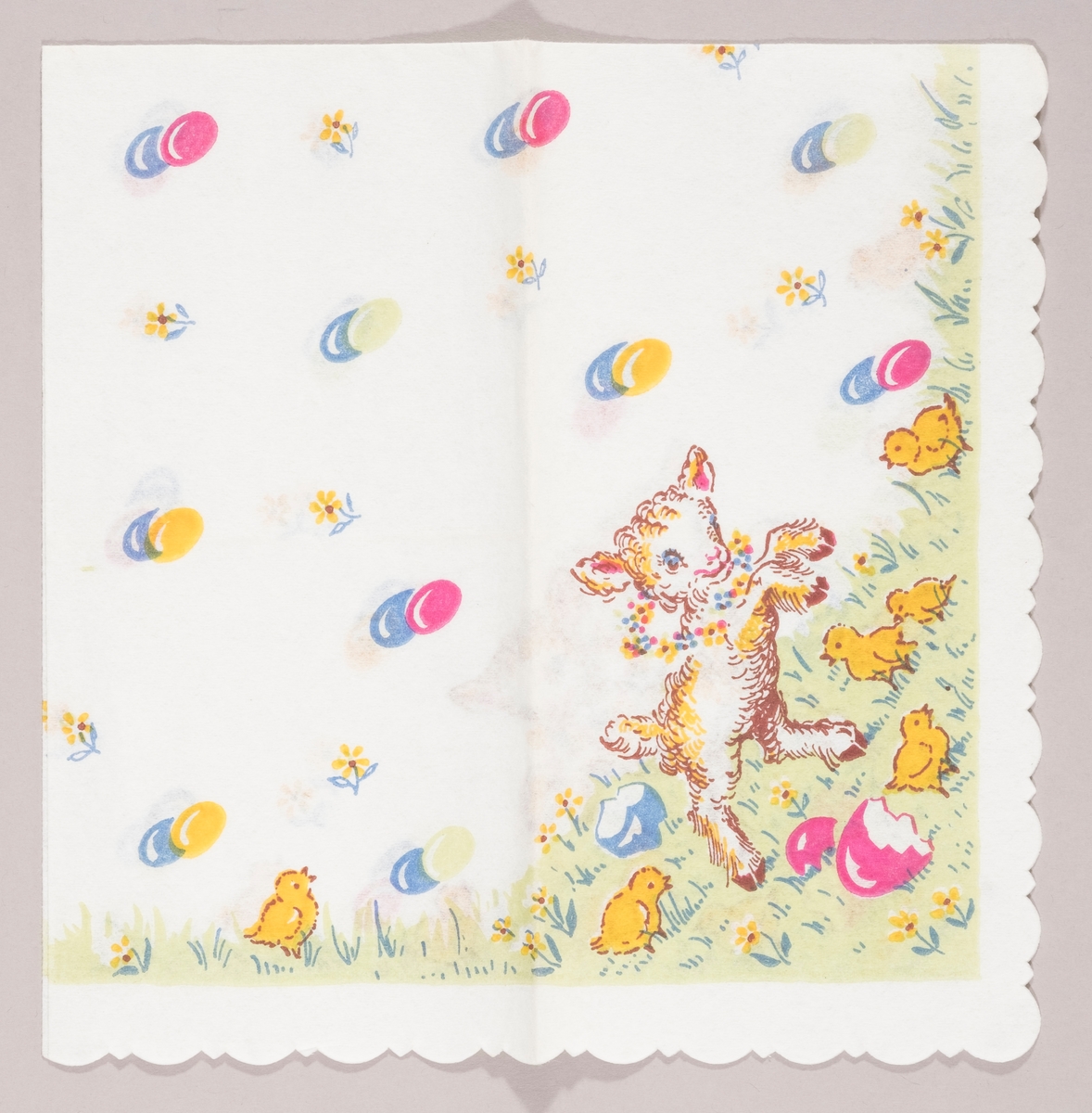 Et påskelam med en blomsterkrans om halsen. Kyllinger på en gressplen med skaller fra påskeegg. Påskeegg i par og gule blomster.