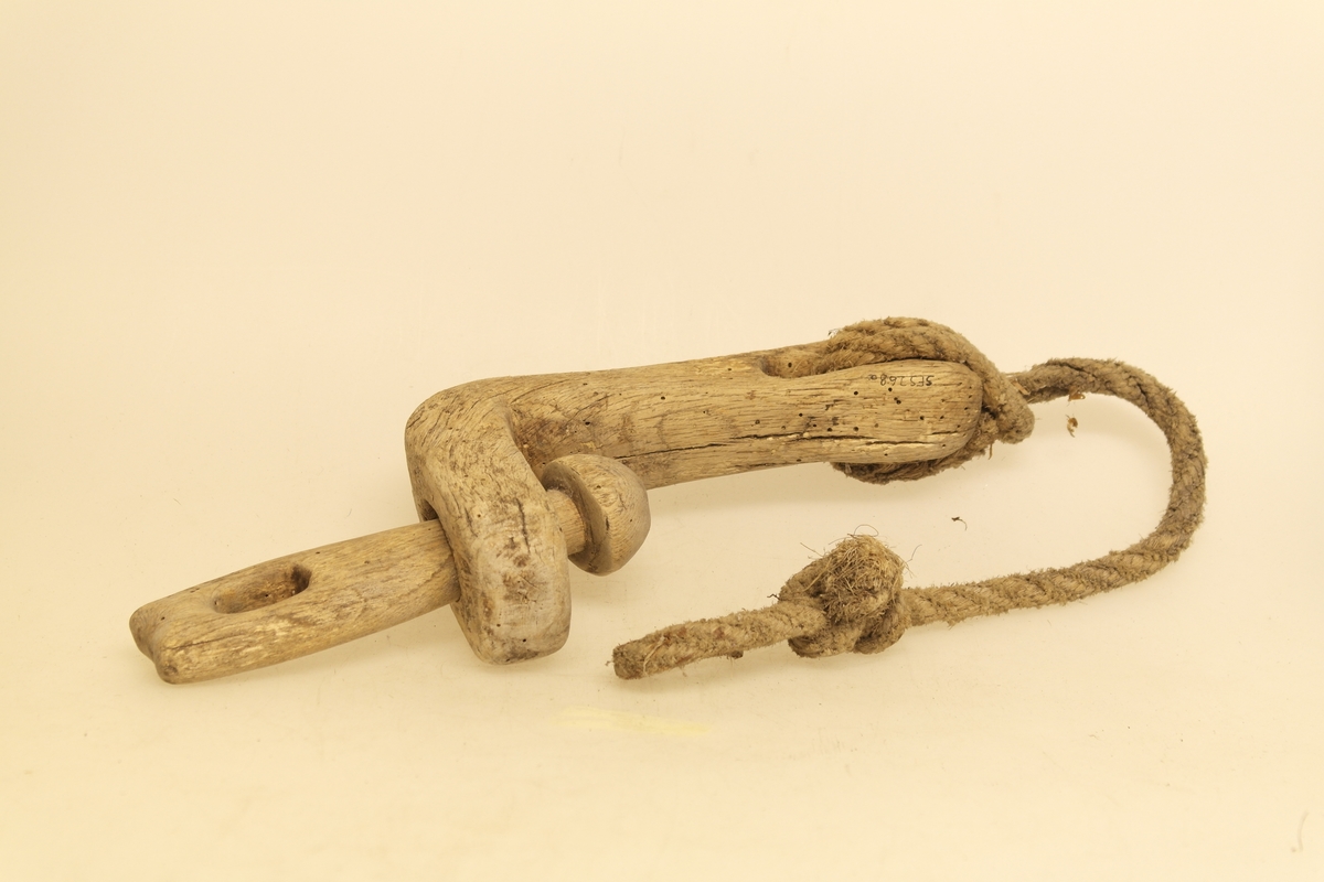 Veggband/Lekkjend i skåret eik. To ledd er skåret ut av samme trestykke, slik at begge kan svinge rundt. Utsparing i hver ende av leddene. Det er bundet et rep i det ene leddet.