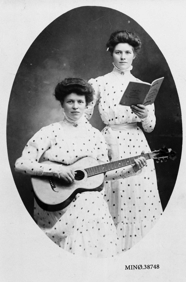 To kvinner, den ene spiller gitar.