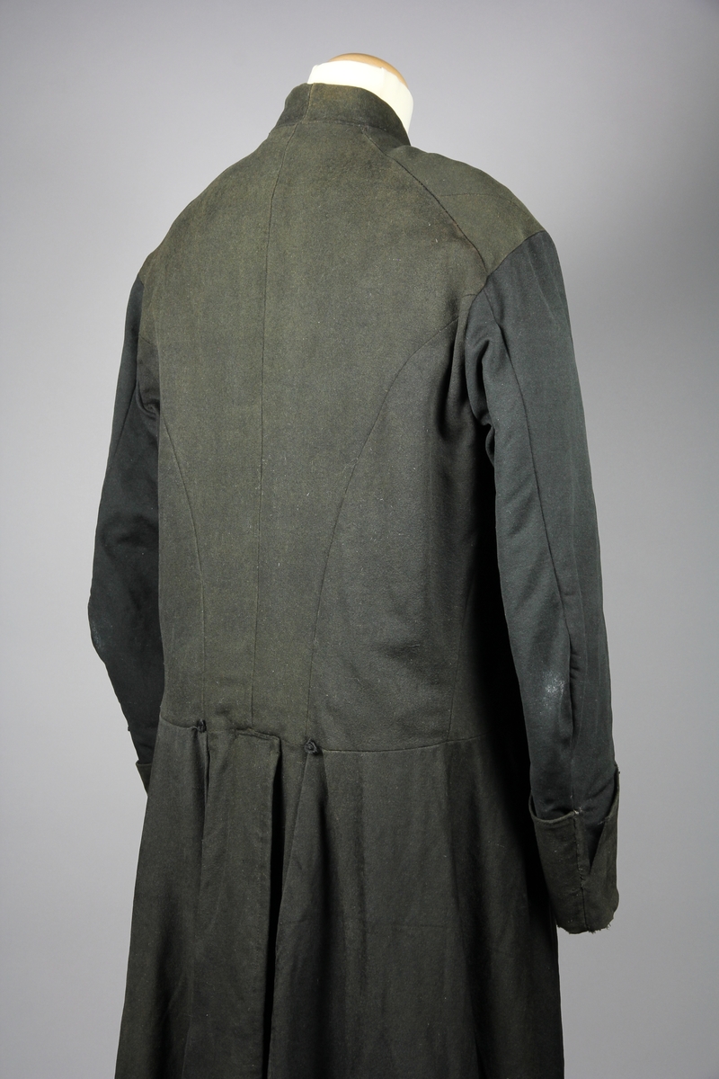 Rock av svart tuskaftsvävt yllekläde. Rocken har en 3,5 cm hög ståkrage. Ärmarna har två längsgående sömmar och 11 cm breda uppslag. Ryggstycket är sammanfogat av fyra våder. Vid axlarna är en trekantig kil infälld på var sida. Troligen en besparing. I höfthöjd har rocken en mittsöm som löper hela vägen runt. Skörten är skurna med stort omfång och rundade. I mitten bak är båda skörten förlängda med en remsa som överlappar på höger sida i ett sprund. Nederkanten har på flera ställen infälda stycken, troligen för att utnyttja tyget maximalt eller som lagningar. Rocken stängs fram med 9 par hyskor och hakar av grov mässingstråd.

Fodret är sytt av minst tre olika tyger. Överst ett grövre grårandigt linnetyg med två infällda innerfickor. Ärmarna är fodrade med oblekt linne och har vaddering av bomullsvadd. Nederst i båda ärmsluten finns rester av blåfärgade linneremsor. Kanske ett tidigare fodertyg eller ett mellanlägg. Rockens nedre foderdel är av ett tunt linne eller bomullstyg med tryckt mönster i brunt på ljusbrun botten. Möjligen är den övre delen av fodret yngre än den nedre. Slitaget på den övre är mindre än på de nedre. Hela rocken är handsydd, men det förekommer lagningar och bättringar med raksöm från symaskin. Det finns flera mindre och några större hål samt sömmar som släppt.