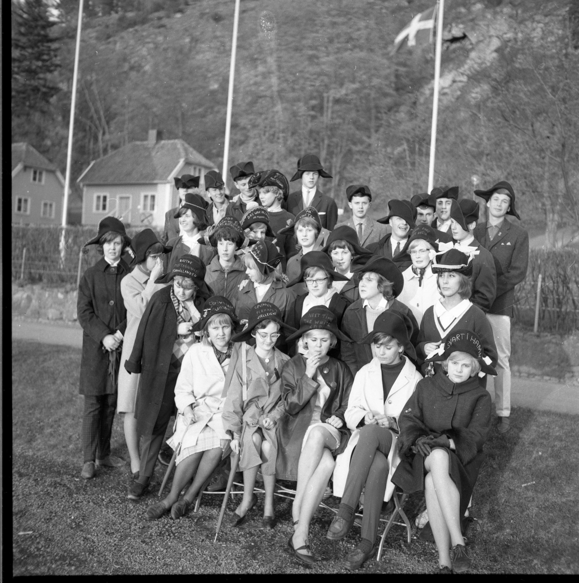 Abiturienter samlade vid torgets östra del, på en slänt nedanför Bergsgatan, 1964. I bakgrunden Grennaskolan. I gruppen finns Berit Johansson, Berit Larsson (3:e raden fr höger), Bo Palm, Susanne Arding, Iris Gustafsson, Zoli Axelsson, Morgan Karlsson, Nils-Erik Olofsson, Ann-Christin Haglund, Gullan Hagström, Britt-Marie Karlsson, Lena Simonsson, Ewa Heldebrandt, Ingrid Lööf, Bo Palm, Thorsten Rydberg, Gunborg Svensson m fl.