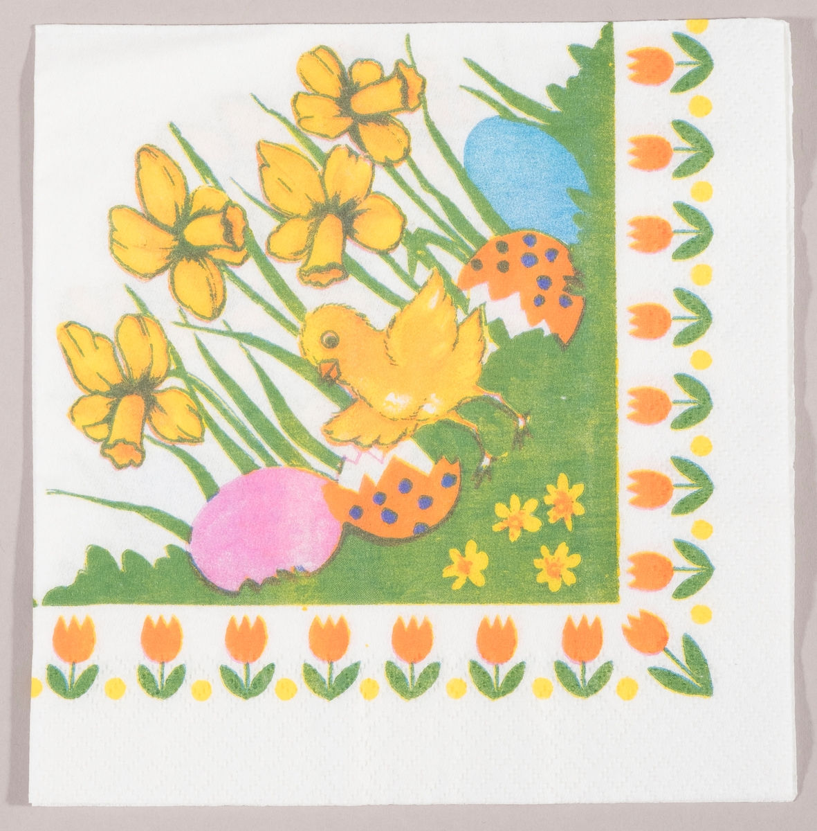 En kylling med utbredte vinger står mellom påskeliljer og to skaller av et påskeegg,og et rosa og et blått påskeegg. En rekke med tulipaner langs kanten.