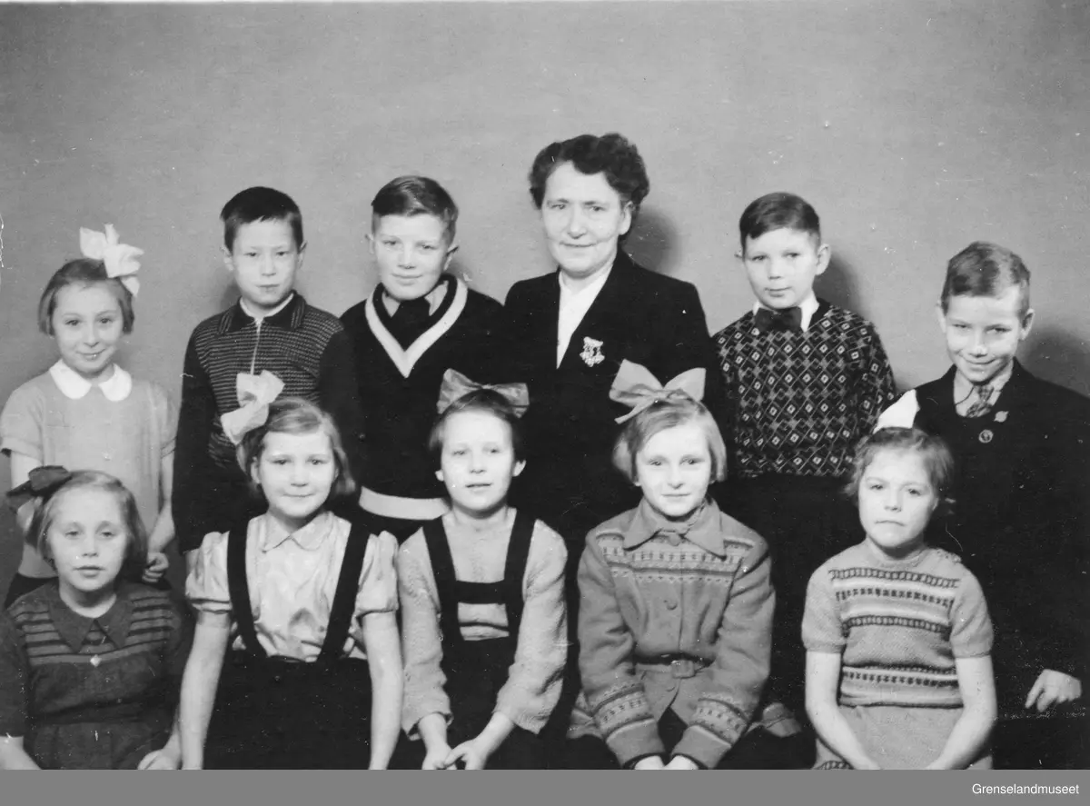 Jordmor Nelly Lund fotografert sammen med ti tunnelbarn, 10 år etter krigens slutt. 