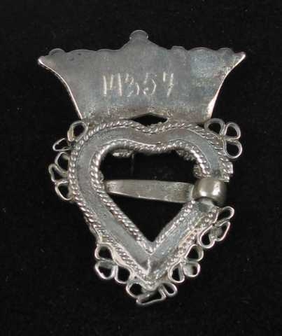 Krusesprette av sølv med løkker. Krona er loddet til hjertegrinda. På midten har den en tredobbel diamantkruse omgitt av små perler og perlekruser. Langs kanten er det pålagt tvinnetråd. Hjertegrinda er utvendig og innvendig kantet med tvinnetråd. På forsida er den dekket av perlekruser og diamantkruser. (En perle mangler.) Langs kanten er det trådløkker satt sammen tre og tre. (Deler mangler.)Tornen er festet på tvers av hjertegrinda. Krona ser ut til å være forgylt.