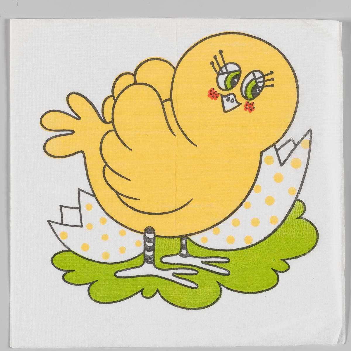 En kylling og skallet av ett egg på ett grønt underlag.