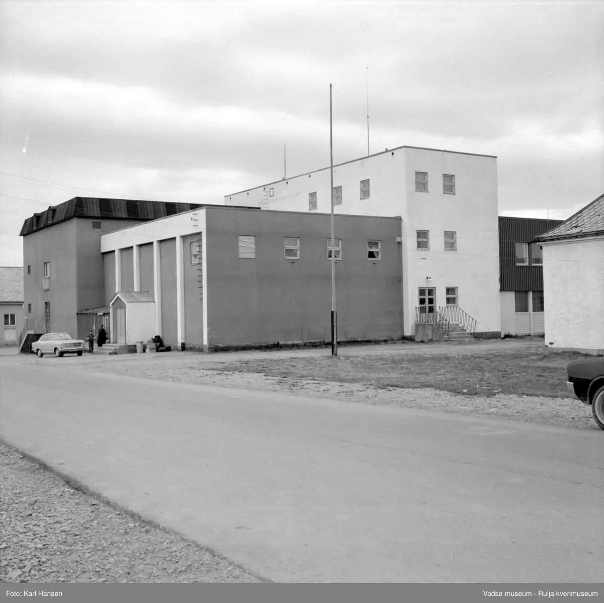 Vadsø samfunnshus 1972. Bildet er tatt mot sør og viser den eldste delen som sto ferdig i 1955 og rommet bl.a. kino og svømmebasseng, kafe og festsal / gymsal. Man ser litt av den nye delen, mot vest, den sto ferdig i 1964, med bl.a. ny festsal  og garderober. Foran til høyre litt av Finmarksbibliotekets bygning.
