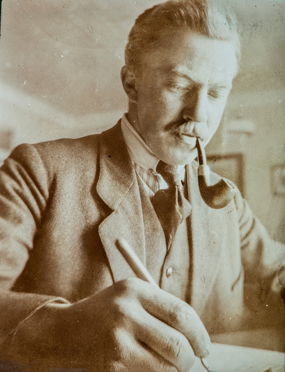 Mann med pipe skriver. Benningstad. Olaf Benningstad(?)