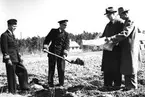 F6 Karlsborg 1949. Det första spadtaget för de 4 husen som skulle byggas för i första hand flottiljens anställda. Från vänster: Intendenten kapten Erik Bodin, chefen F6 överste Sten Gösta Hård, byggmästaren Birger Andersson, verkmästaren Åberg. Albumet är en del av en donation från Karl-Axel Hansson, Karlsborg. Förteckning över hela donationen finns i albumet samt som Word-dokument.