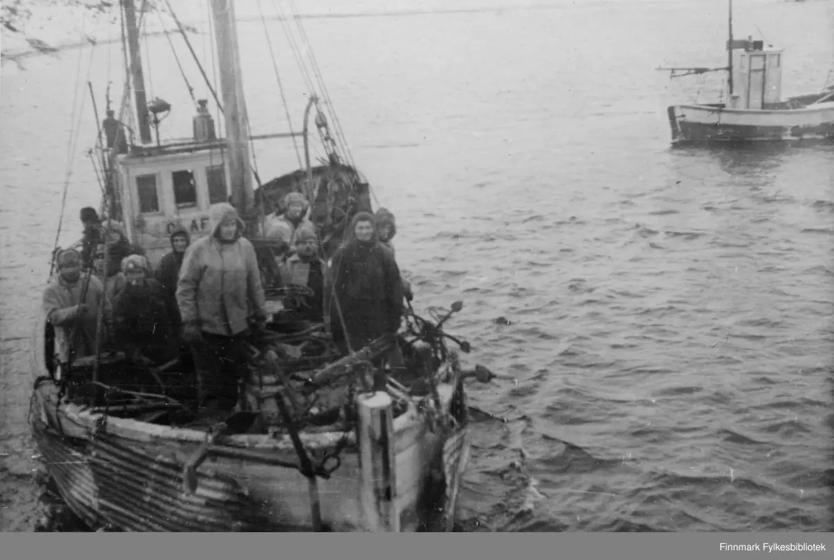 En norsk liten fiskebåt, på styrhuset står det OLAF (m/k Olaf-F35LB). Det er Thoralf Jensen jr som er skipper. Ove Nilsen fra Kalak og Rudolf Grønnbeck fra Bekkarfjord vekslet på å være mannskap. På dette bildet, framme på babord side ser vi Ove Nilsen. Klærne skiller seg ut fra soldatenes påkledning. 

Thoralf Jensen jr. og båten hans var underlagt militær kommando og stasjonert i Holmefjord i Porsanger.  De som er ombord er et befal og soldater fra Bergkompani 2. De skal levere forsyninger til soldatene som er stasjonert i Holmbukt. Isen er 10-20 cm tykk. Skipperen er redd for båten, og protesterer til ingen nytte. Soldatene bruker hesten og finner tak i bølgeblikkplater de rigger til på sidene av båten. 
Båten til høyre i bildet er m/k "Glimt" av Sørøya, F64HV, 29fot og Skipper Johan Eilertsen fra Breivikbotn. Båten var i tjeneste for Bergkompaniet da den ble tatt 21.02.1945 i det som er omtalt som "Tragedien i Sortvik". Johan Eilertsen og Ragnar Jensen, begge fra Breivikbotn på Sørøya, mistet livet. 

Bildeserien "Frigjøringen av Finnmark 1944-45" viser et unikt materiale fotografert av soldater i Den Norske Brigade, 2. Bergkompani under deres oppdrag "Frigjøringen av Finnmark" som kom i stand under dekknavn "Øvelse Crofter". Fakta rundt dette bildematerialet illustrerer iflg. vår informant, George Bratli: "2.Bergkompani, tilhørende Den Norske Brigade i Skottland,  reiste fra Skottland 30. oktober 1944 med krysseren «Berwick» til Scapa Flow på Orkenøyene for å slutte seg til en større konvoi som skulle være med til Norge. Om bord på andre skip var det mange russiske krigsfanger som hadde vært på tysk side og som nå ble sendt hjem. 
2.Bergkompani forlot havn 1.november 1944 og kom til Murmansk, Sovjetunionen, 6. november 1944. 
De ble her lastet om og fraktet til Petsamo, Sovjetunionen, hvor de ankommer 11.november 1944. 
Kompaniet reiser så til Sandnes utenfor Kirkenes og blir forlagt der frem til 26.november 1944. De flytter så videre til Skiippagurra. 
Den 29.november reiser deler an kompaniet til Rustefielbma og Smalfjord og noen drar opp på Ifjordfjellet. 

17. desember ankommer resten av kompaniet til Smalfjord. 30.desember blir en avdeling sendt til Hopseide og 8. januar 1945 blir noen sendt til Kunes.
Den 14. januar er kompaniet delt og ligger i Kunes, Kjæs, Børselv, Hopseide og Smalfjord.
5. februar 1945 blir 3.tropp sendt over Porsangerfjorden for å operere i Olderfjorden. Her var de i kamp og hadde tap i  Billefjord og Sortvik.
8.mars 1945 kom noen til Renøy og 12. mars kom første del av kompaniet til Brennelv.
7.mai begynte kompaniet å bygge ny kai i Hambukt.
19. mai ble de som hadde falt begravd i Lakselv.
8. juni ble kompaniet flyttet fra Brennelv til Tromsø for så å bli sendt videre til Mo I Rana 16.juni."

Nasjonalbiblioteket har et hefte fra 1983 skrevet av Krigsinvalideforbundet, med intervjuer med soldater og deres opplevelser: 
https://www.nb.no/items/5d58d366b390666f671f57078519c2c7?page=0&searchText=Det%20glemte%20kompani%20-%202.%20Bergkompani%20og%20frigj%C3%B8ringen%20av%20Finnmark

https://www.arkivverket.no/utforsk-arkivene/andre-verdenskrig/befolkede-jordhuler-kjokken-i-det-fri-og-midlertidige-begravelser-privat-bildesamling-etter-soldat-i-2.bergkompani
