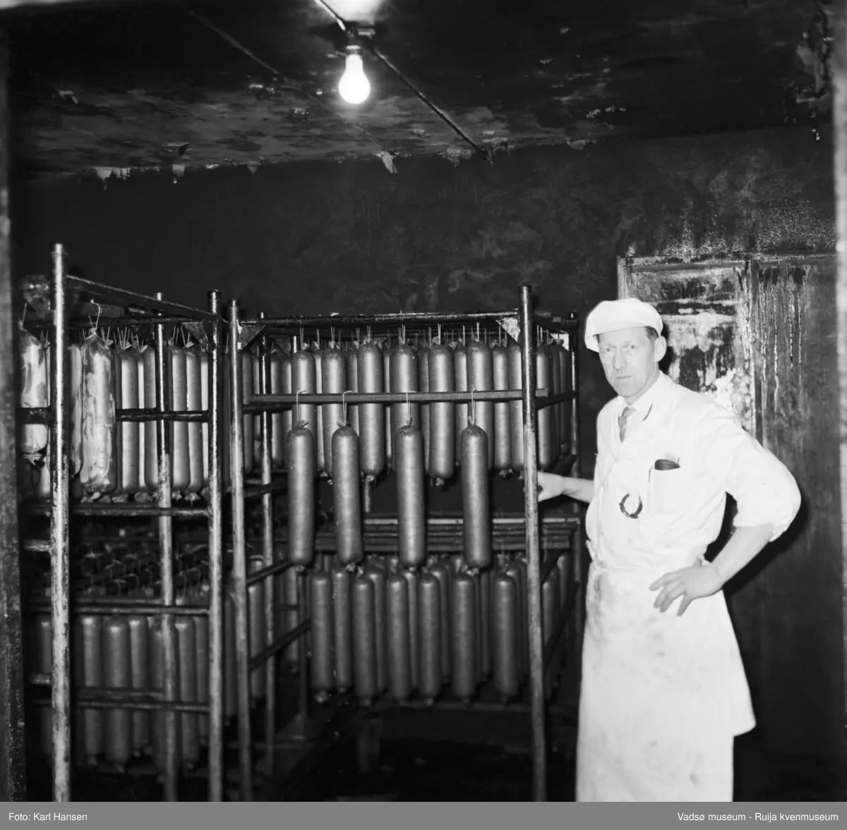 Nord-Norges salgslag Vadsø, 1964. Spekepølser i røykeri/klimarom . Avbildet person; produksjonsleder Hans Petter (HP)  Hansen.