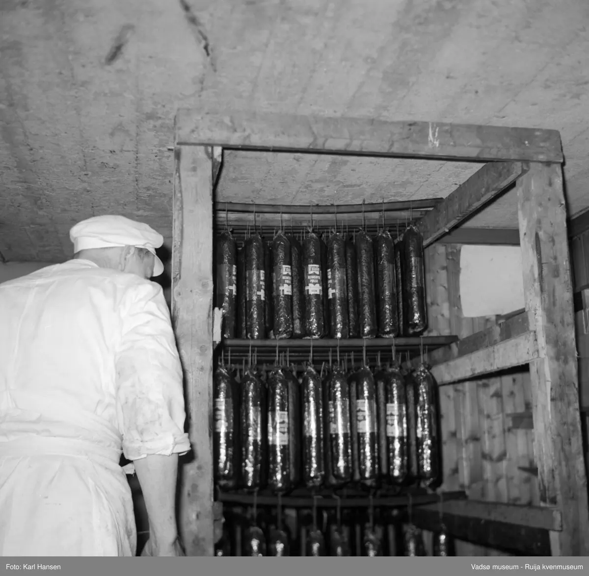 Nord-Norges salgslag Vadsø, 1964. Spekepølser i røykeriet. Avbildet person; produksjonsleder Hans Petter (HP) Hansen.
