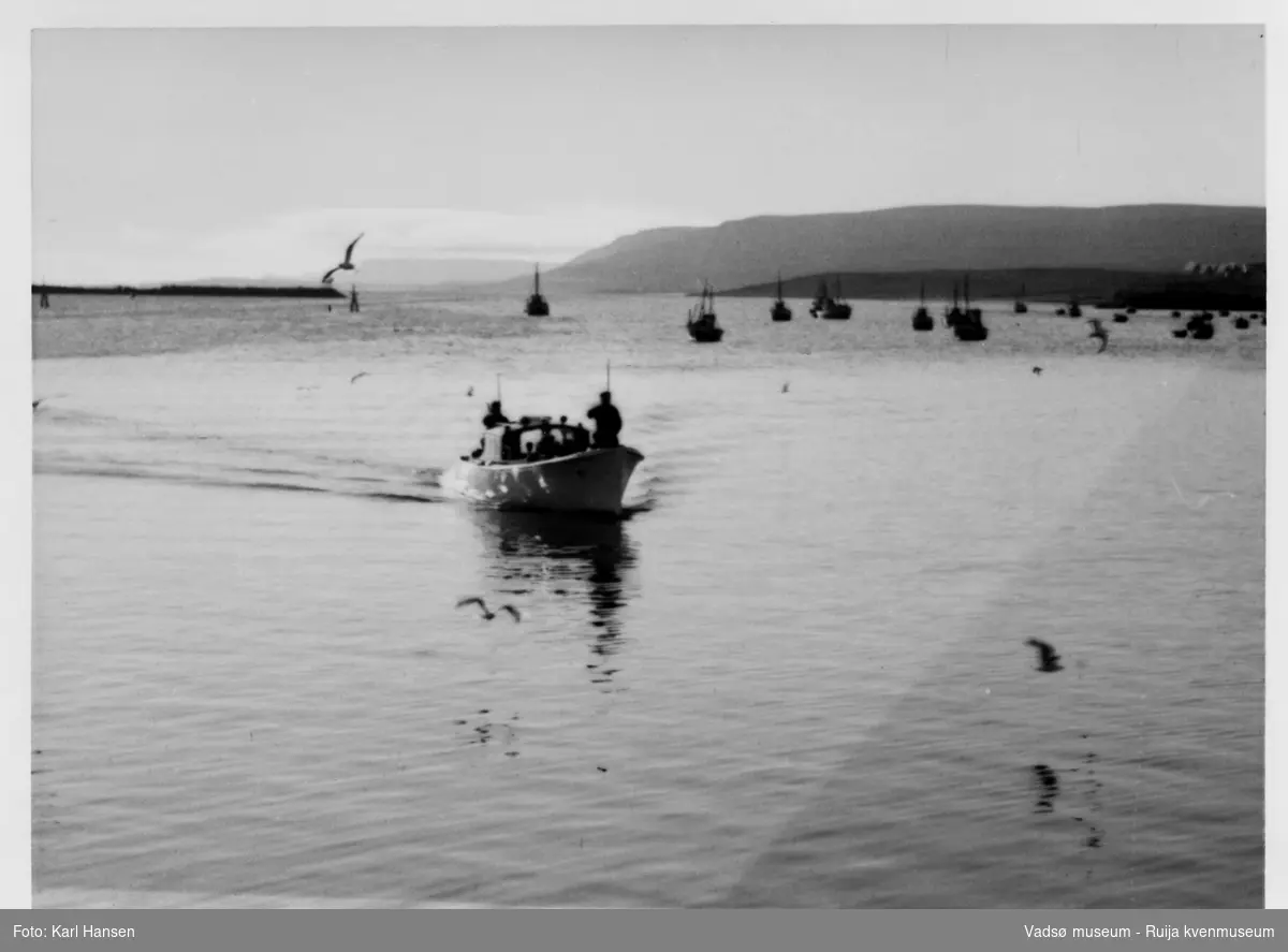 Vadsø. Kongebesøk i Vadsø 1950. Båt på havna på vei mot land. Trolig sjaluppen fra Kongeskipet Norge. Kong Haakon og kronprinsfamilien besøkte Vadsø 25.-26.7.1950 i forbindelse med en større rundreise i Nord-Norge sommeren 1950. Under besøket sto "biltur gjennom byen" og "besøk på sykehuset" på programmet. Kilde: Det kongelige hoff, arkivet