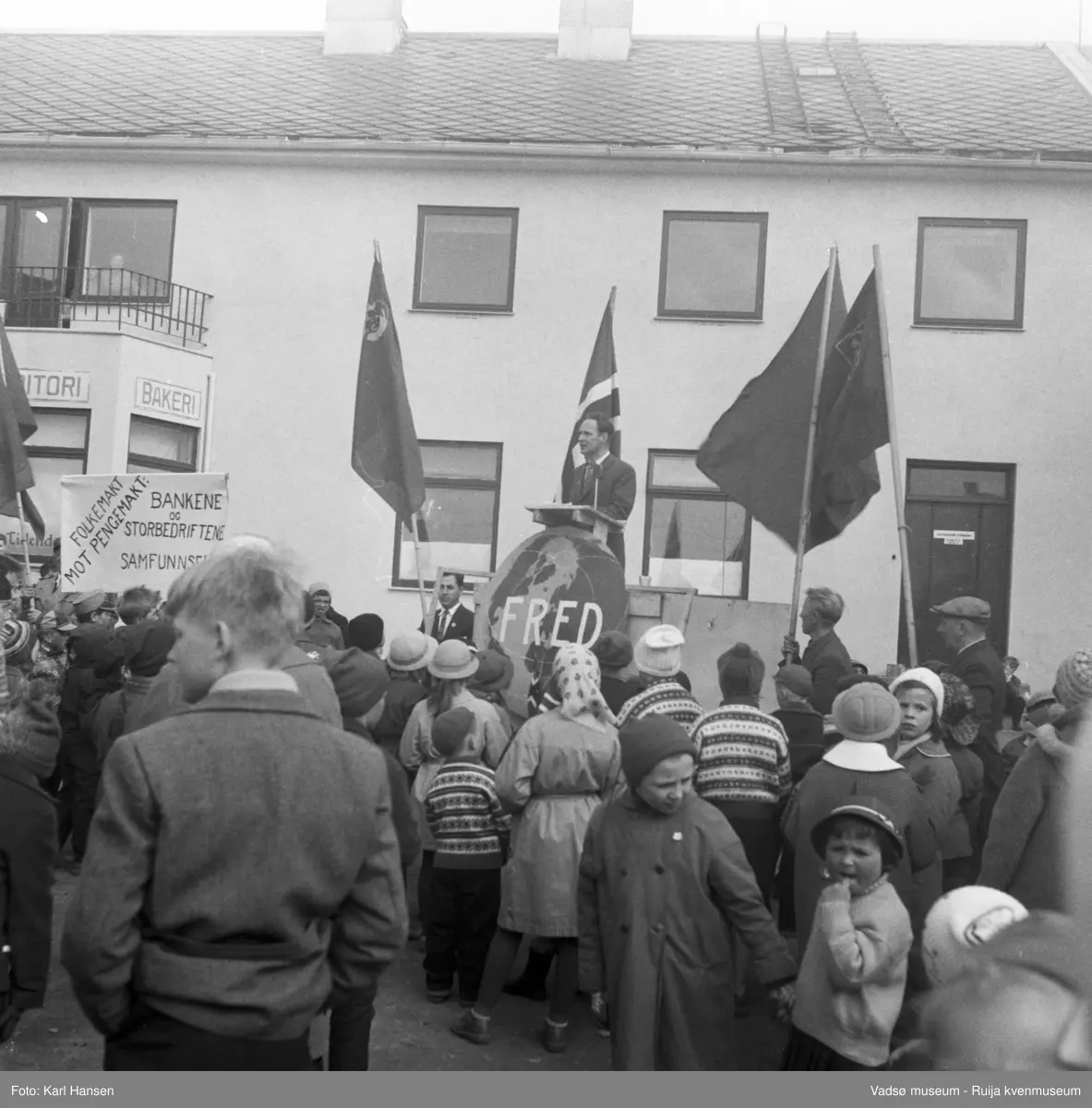 Vadsø 1.mai 1960. Samling og tale på Torget. Bygningen bak taleren er Henriksens bakeri.