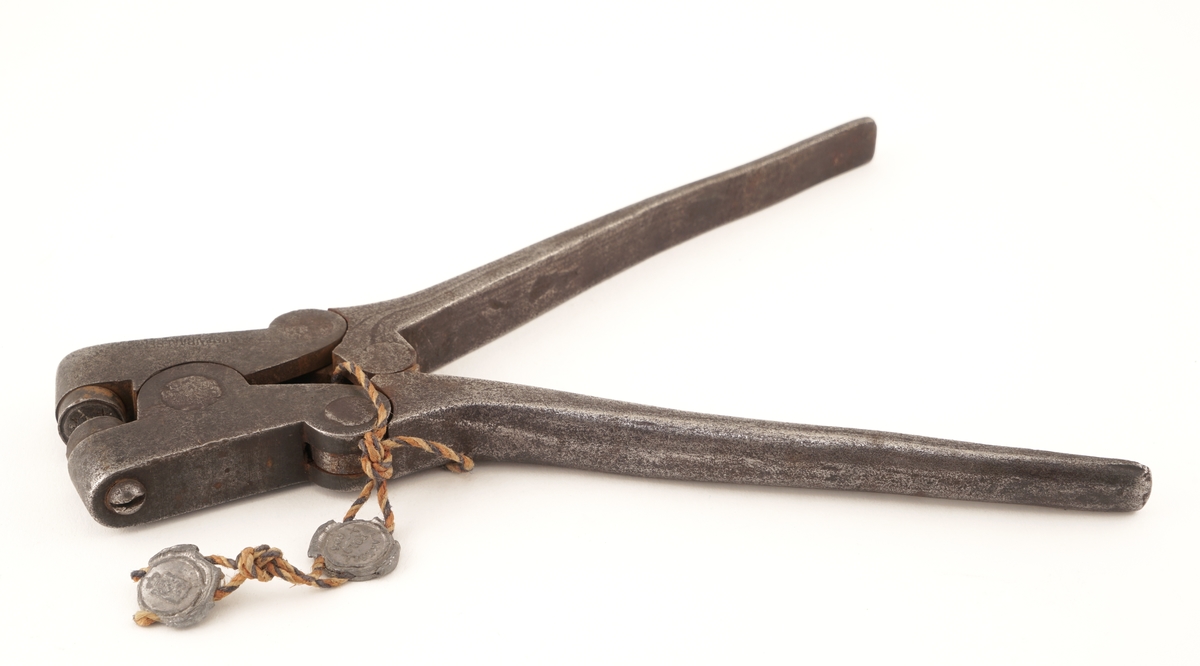 Plomberingstang av jern med tråd og to blyplomber festet til.