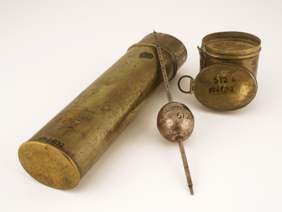 Alkoholmeter av sølv i etui med lokk. Lokket inneholder et ekstra rom for oppbevaring av  vekter til alkoholmeteret. Etuiet inneholder to rom for plassering av to alkoholmetere. Det mangler ett alkoholmeter og alle vektene