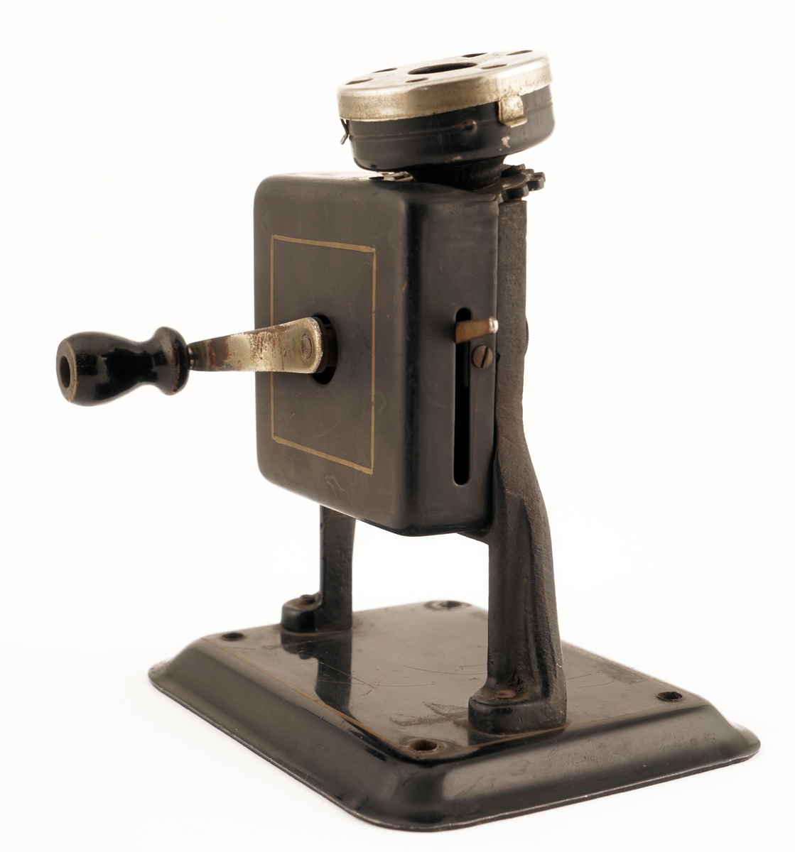 Blyantspisseapparat av  sortlakkert metall med dreiet håndtak i tre.