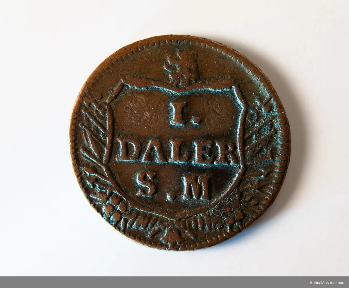 1 daler silvermynt 1717, "WETT OCH WAPEN", koppar, Stockholm.
Mynt präglat under Karl XII:s regeringstid.

Åtsidan: 
Frånsidan: I DALER S.M. på tre rader.
Myntets ytterrand refflad, vinkelrätt.

Material: koppar med tvångsvärde 1 daler silvermynt.

Karl XII 1682 - 1718, kung av Sverige 1697-1718.
Förvärvsdatum okänt.