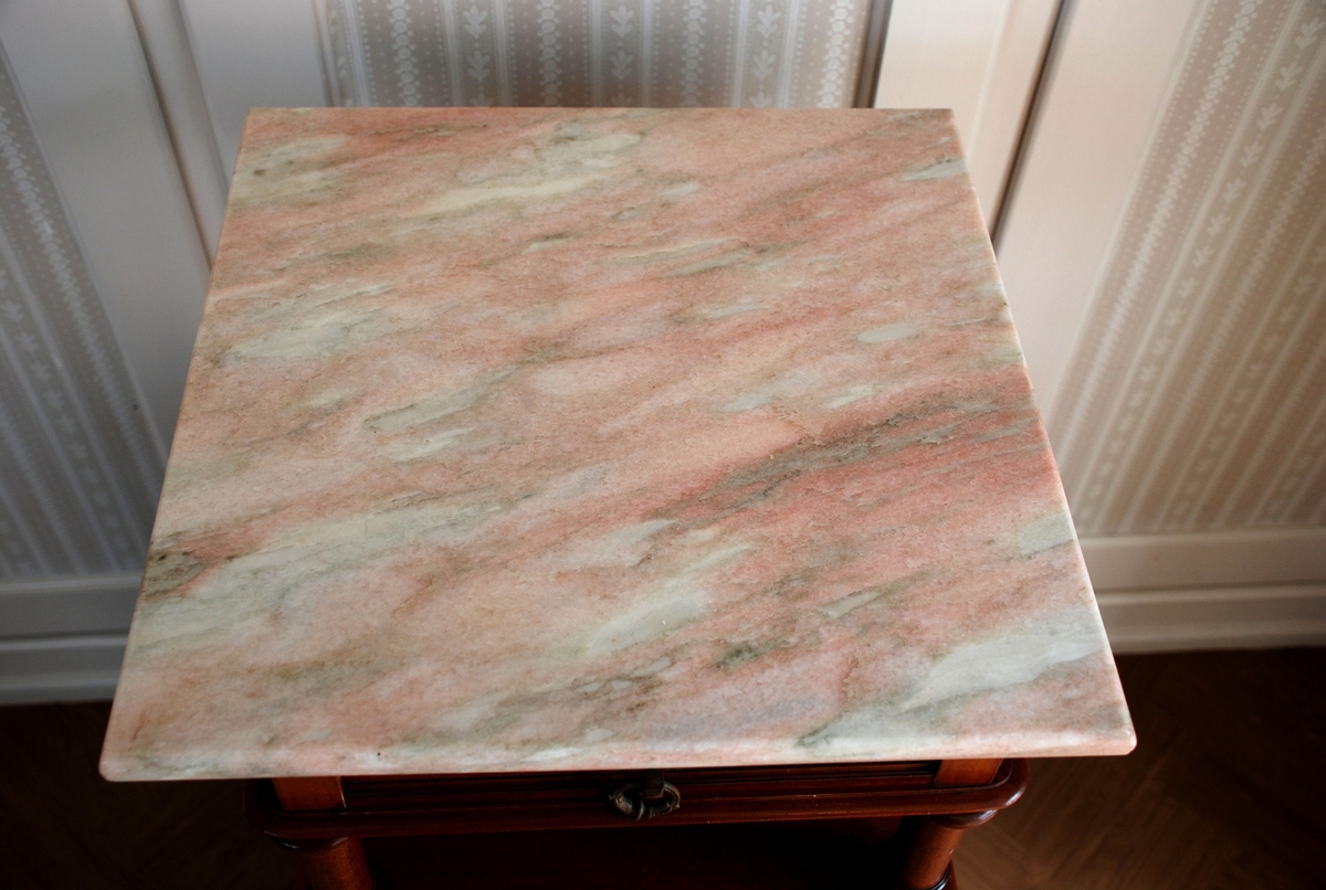 Mørk brunt nattbord med marmorplate på toppen. En skuff og skap. Åpen hylle over skapet. Marmorplate på toppen.