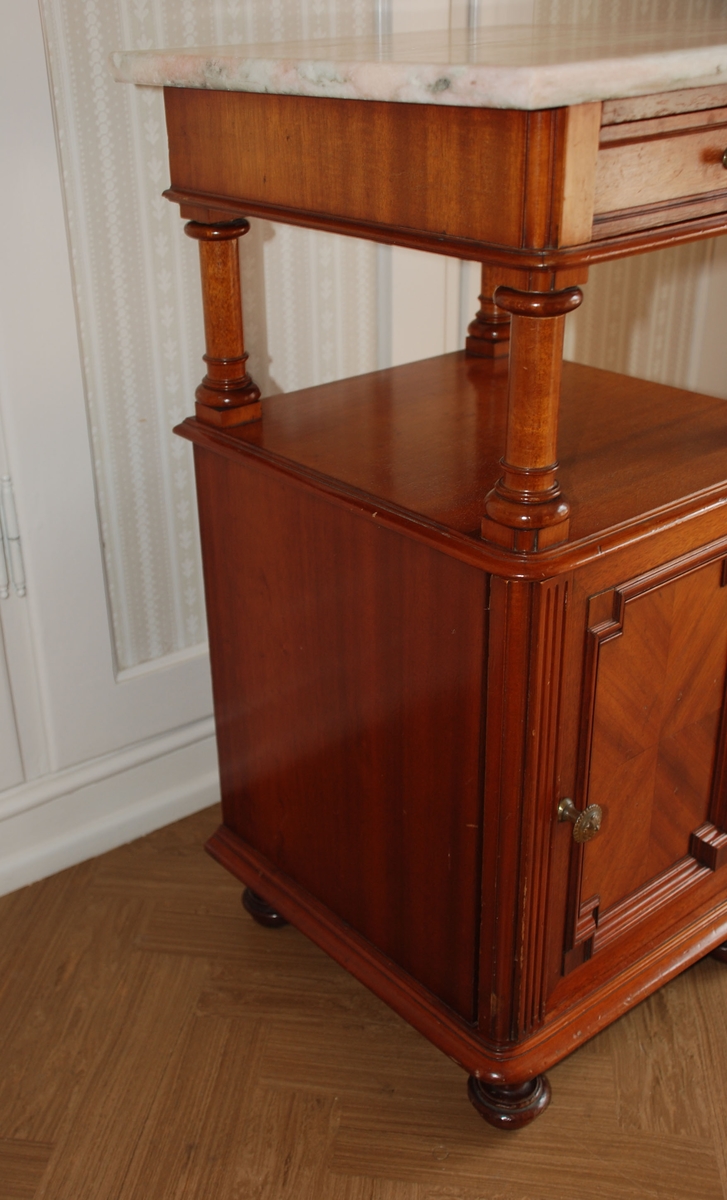 Mørk brunt nattbord med marmorplate på toppen. En skuff og skap. Åpen hylle over skapet.