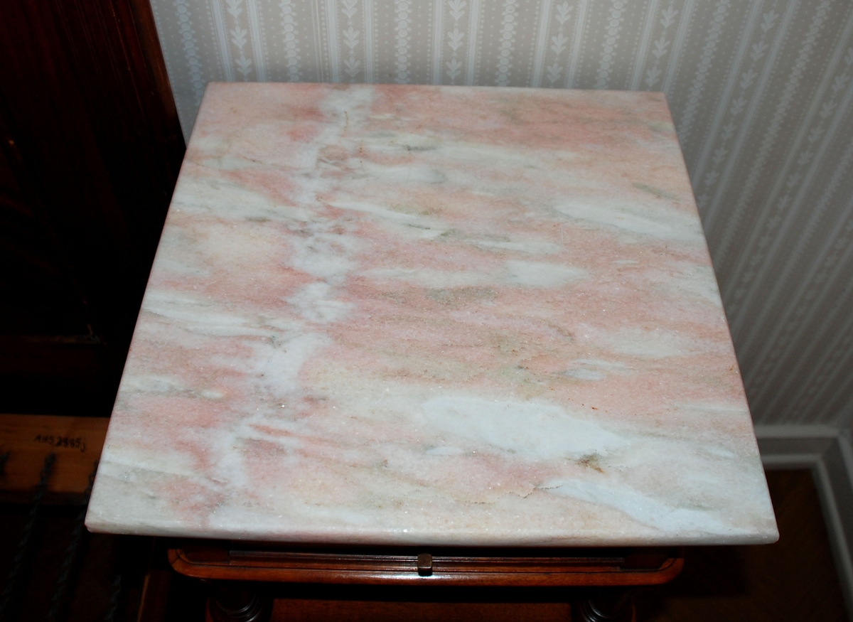 Mørk brunt nattbord med marmorplate på toppen. En skuff og skap. Åpen hylle over skapet.