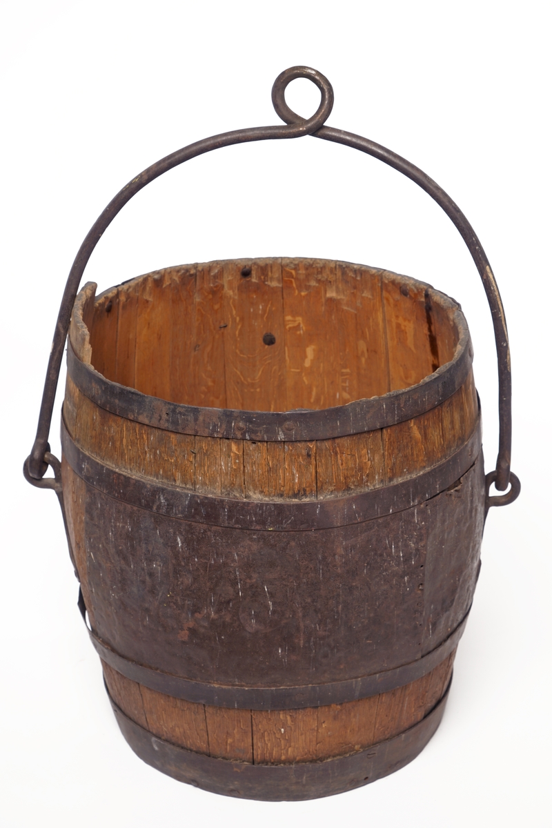 Tretønne med hank av metall, forsynt utvendig med fire metallringer. Delvis belagt med metallbelegg inn og utvendig for antatt reparasjon av tønnen.