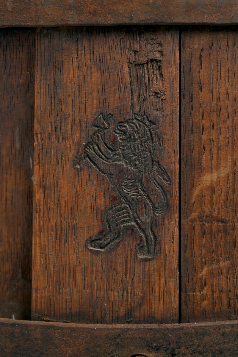 Tretønne (hektolitermål) med 2 bærehanker av metall,.Tønnen er utvendig forsynt med fire metallringer.