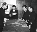 F6 Karlsborg 1954. Kapten Öhrlund 2. Divisionen informerar om ett företag och anfallsmetod för från vänster fänrik Johansson (Savberg), fänrik Johannes, löjtnant Norell. Albumet är en del av en donation från Karl-Axel Hansson, Karlsborg. Förteckning över hela donationen finns i albumet samt som Word-dokument.