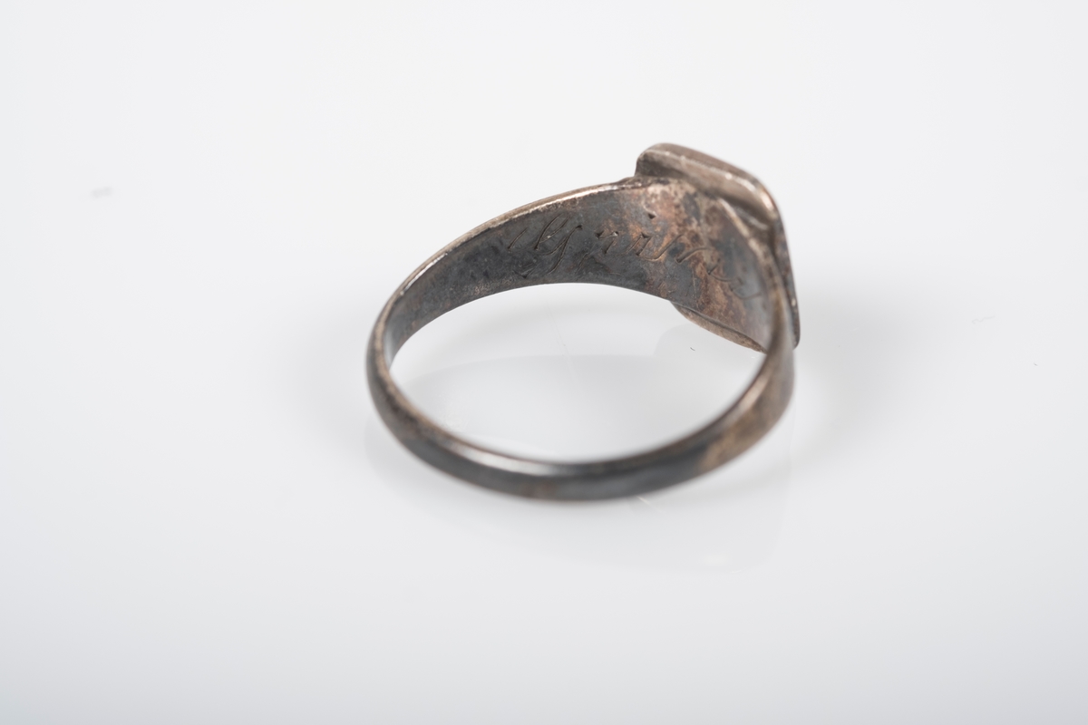Rund ring i med et firkantet monogram hvor initialene D.O er inngravert. På innsiden står det Grini 1943.