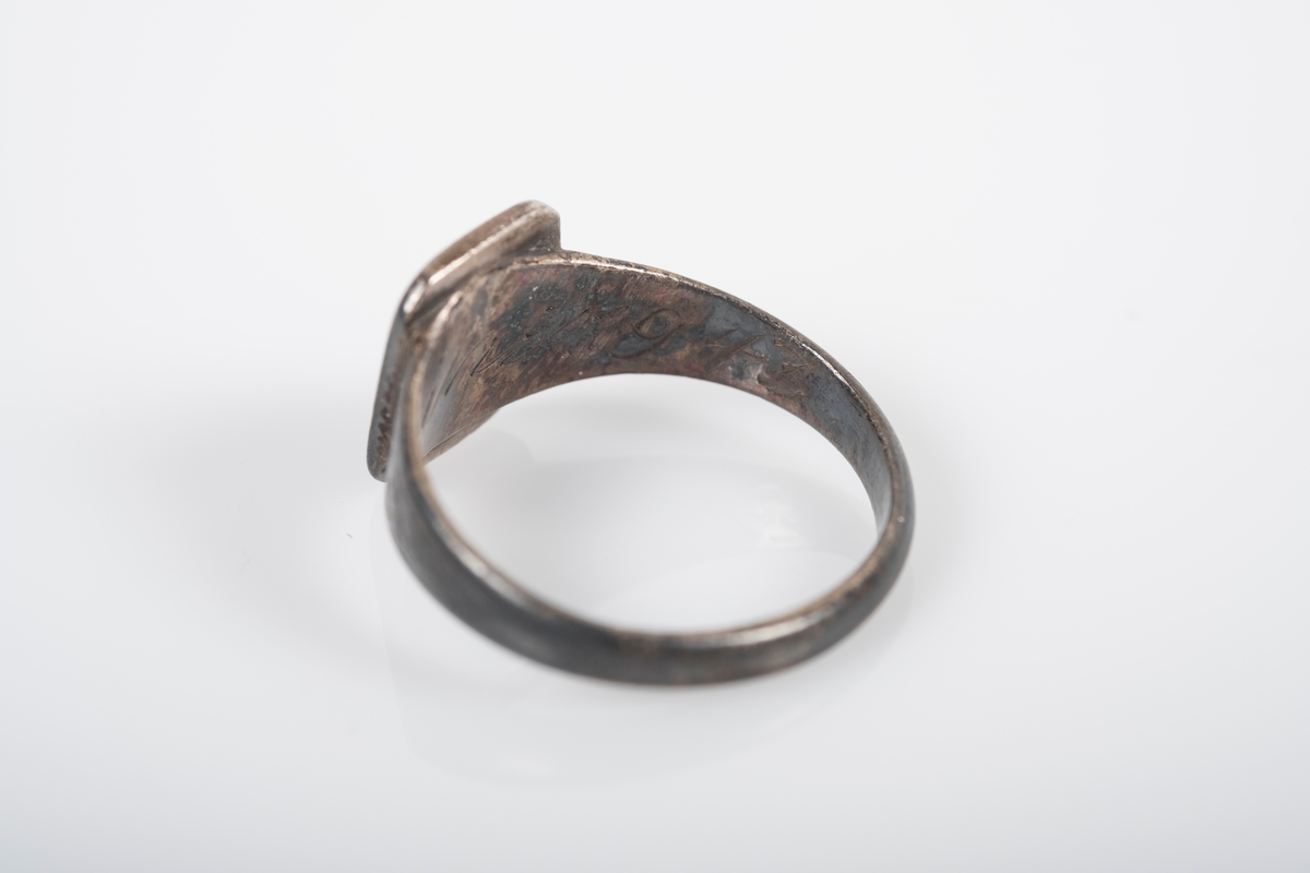 Rund ring i med et firkantet monogram hvor initialene D.O er inngravert. På innsiden står det Grini 1943.