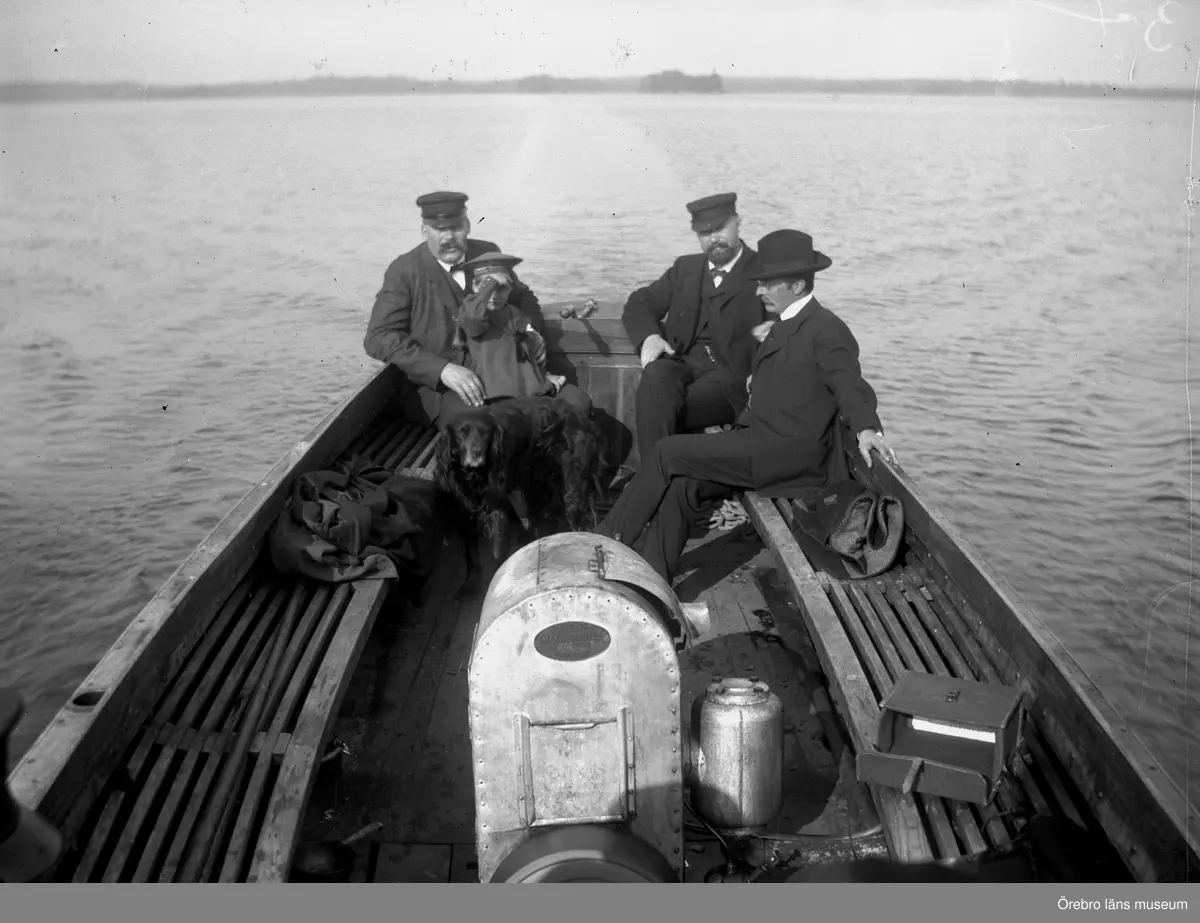 Män, barn och en hund i en båt på Tisaren. Troligen Löföbåten.
Gottfrid, Fredrik och Björn Thermaenius.
En kameraväska på sitsen till höger.