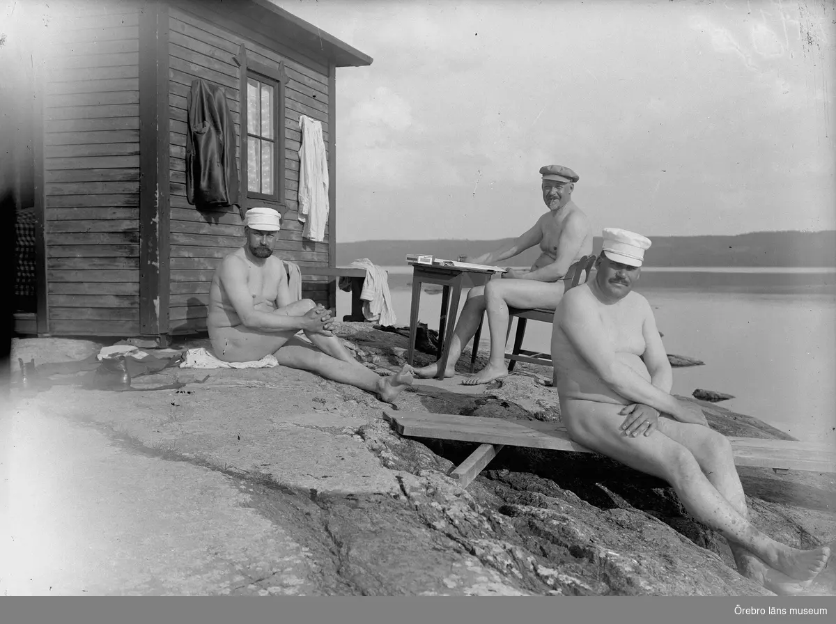 Tre män sittande utanför en stuga på en klipphäll.
Detta är ett styrelsemöte i ett av Thermaenius företag. Det började nere i Hallsberg, men avbröts för att det var för varmt. Mötet flyttades till badhuset på Lövön. Mannen till höger är Gottfrid Thermaenius.