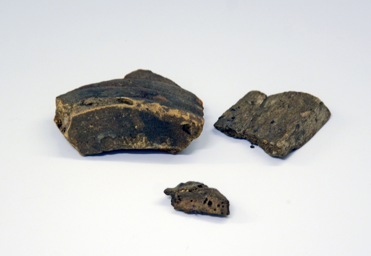 Fra protokollen (J. S. Munch): 
Leirkar i fragmenter, av hovedtypen Rygh.364 med hank ved randen, og negleinntrykk på buken. Hverken form eller dekor kan nærmere bestemmes. Godset er gråsvart, med noe avglattet overflate. 

KBB komm. 2018:
Det er flere forskjellige typer skår; forskjeller både i godsets tykkelse, farge og dekor. Det må være snakk om minst 4 forskjellige leirkar i dette skårmaterialet. Se bilder. I tillegg er det en jern-gjenstand, svært forrustet, muligens en del av en spenne.
Leirkarene: 1 av typen R.364 (el. 365?), 1 grovt (R.354?), 3 små skår fra et spannformet kar + 3 skår fra et nyere leirkar (ser ut til å ha vært tilvirket på dreieskive).
Det første bildet til denne registreringen viser alle deler som er registrert under dette nr.