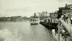 Ångbåten Gustavsberg VI förtöjd vid i Gustavsbergs hamn. Båten byggdes 1896. Gula byggningen skymtar till höger, i bakgrunden Värdshuset och i fjärran Statbyggningen och Ekensberg.
